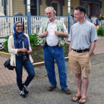 Two men and woman visiting during porch blessing dedication