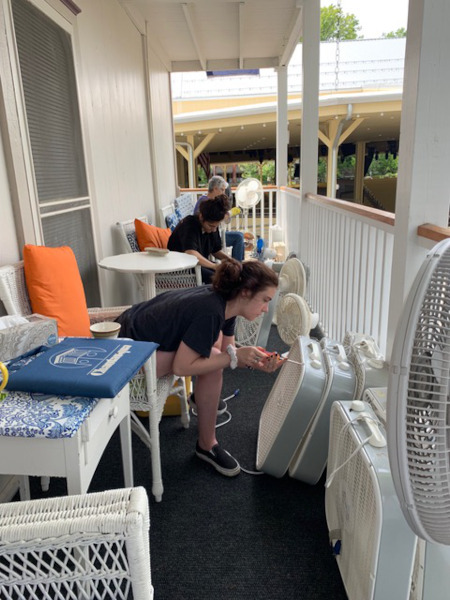 woman fixing fan on shaw porch during a work weekend